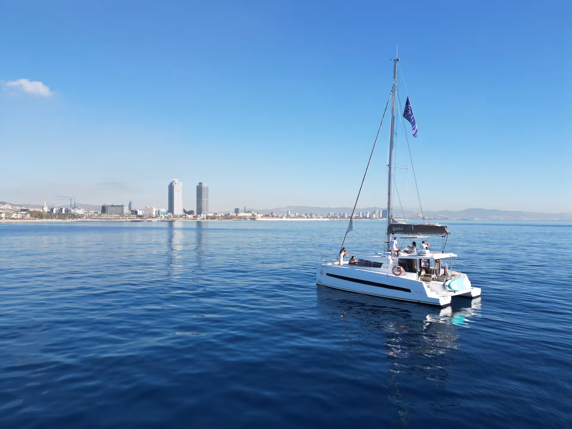 Private yacht dining with a personal chef on a sailing catamaran, cruising calm sea with city skyline views