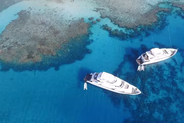 Aerial view of private yachts over turquoise Red Sea reefs near Hurghada, ideal El Gouna snorkeling boat trip