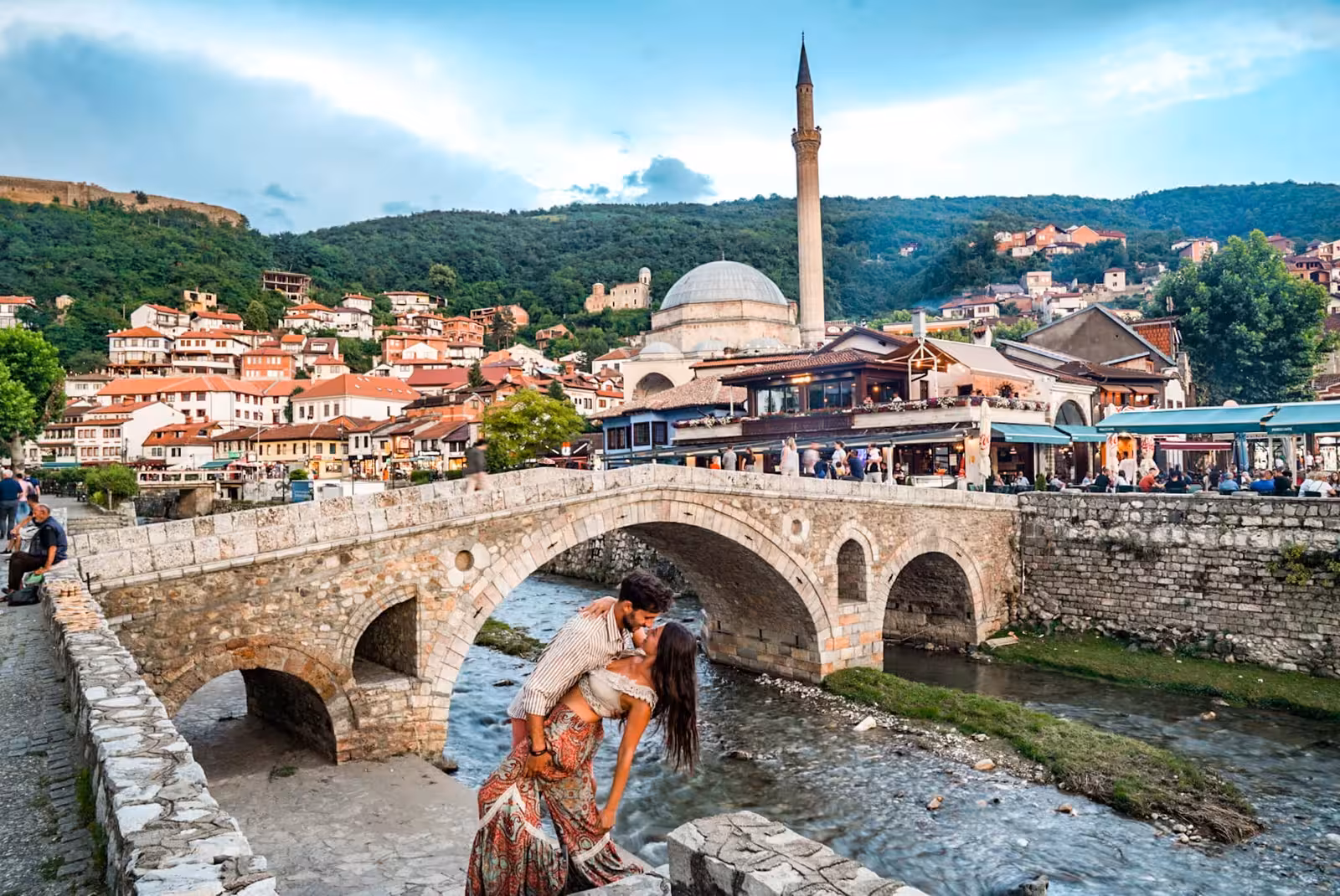 Charming view of Prizren's stone bridge and mosque with lush hills, perfect for day trips in Kosovo.