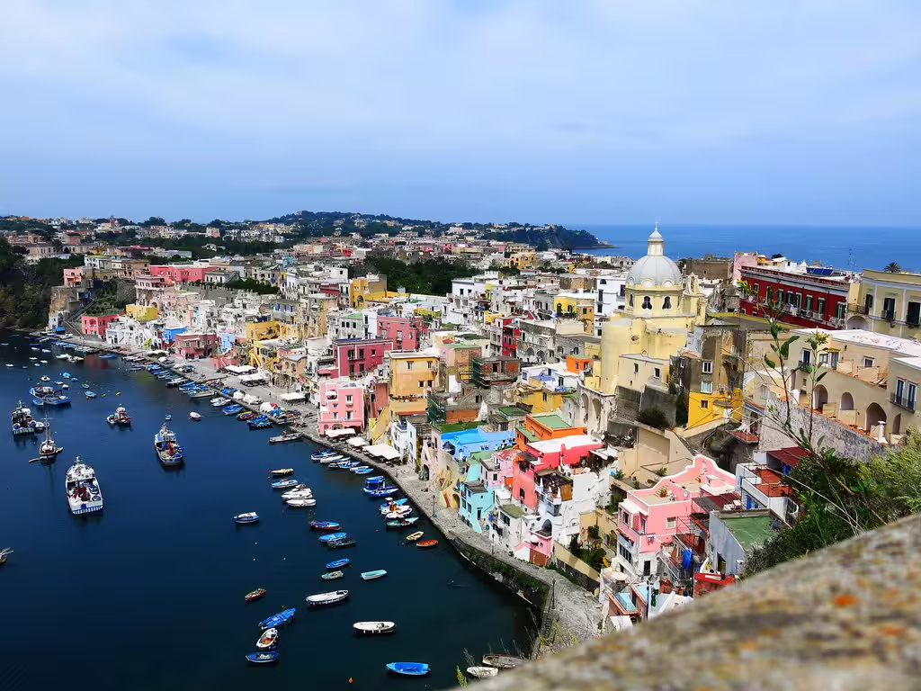 Colorful marina and pastel houses of Procida island seen from above on a scenic boat tour from Ischia, Italy