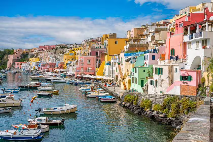 Colorful fishing harbor of Procida island with pastel houses and boats, visited on a small-group cruise from Sorrento