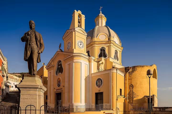 Historic church with a statue in Procida, captured under a clear blue sky during a full-day island tour from Naples.