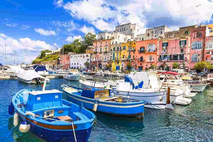 Colorful fishing boats and vibrant buildings line the picturesque harbor of Procida Island, ideal for a scenic tour.