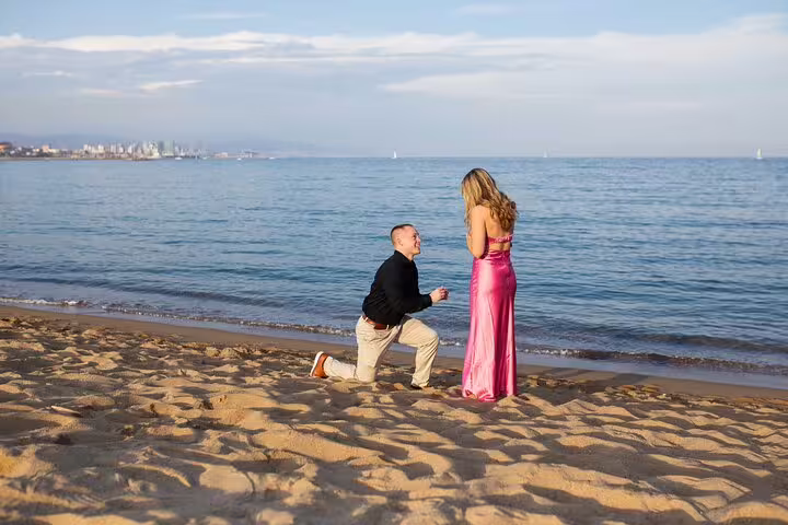Kneeling marriage proposal on Barcelona beach at sunset, captured by professional proposal photographer