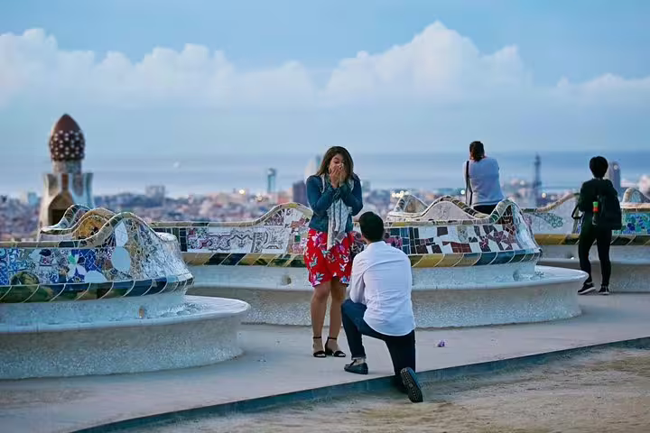 Man kneels to propose to surprised woman, romantic engagement photo shoot with NYC skyline view