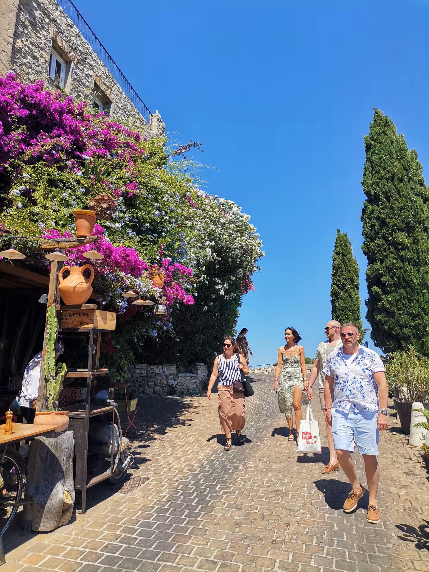 Travelers strolling a cobblestone lane under bougainvillea in a hilltop village on a Provençal Picnic Tour