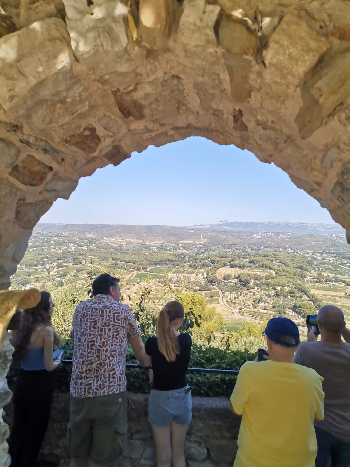Travelers admire sweeping Luberon valley views from a stone arch lookout on a Provençal picnic tour