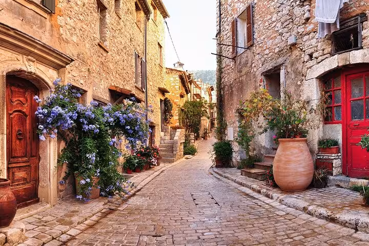 Charming cobblestone street in Provencal village with blooming flowers on countryside tour.