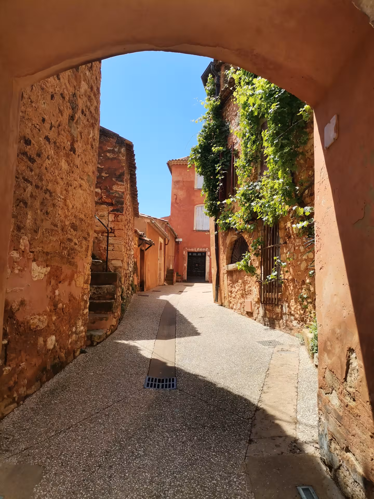 Sunlit ochre alley under stone arch in a Provençal hill village, scenic stop on Provençal Picnic Tour
