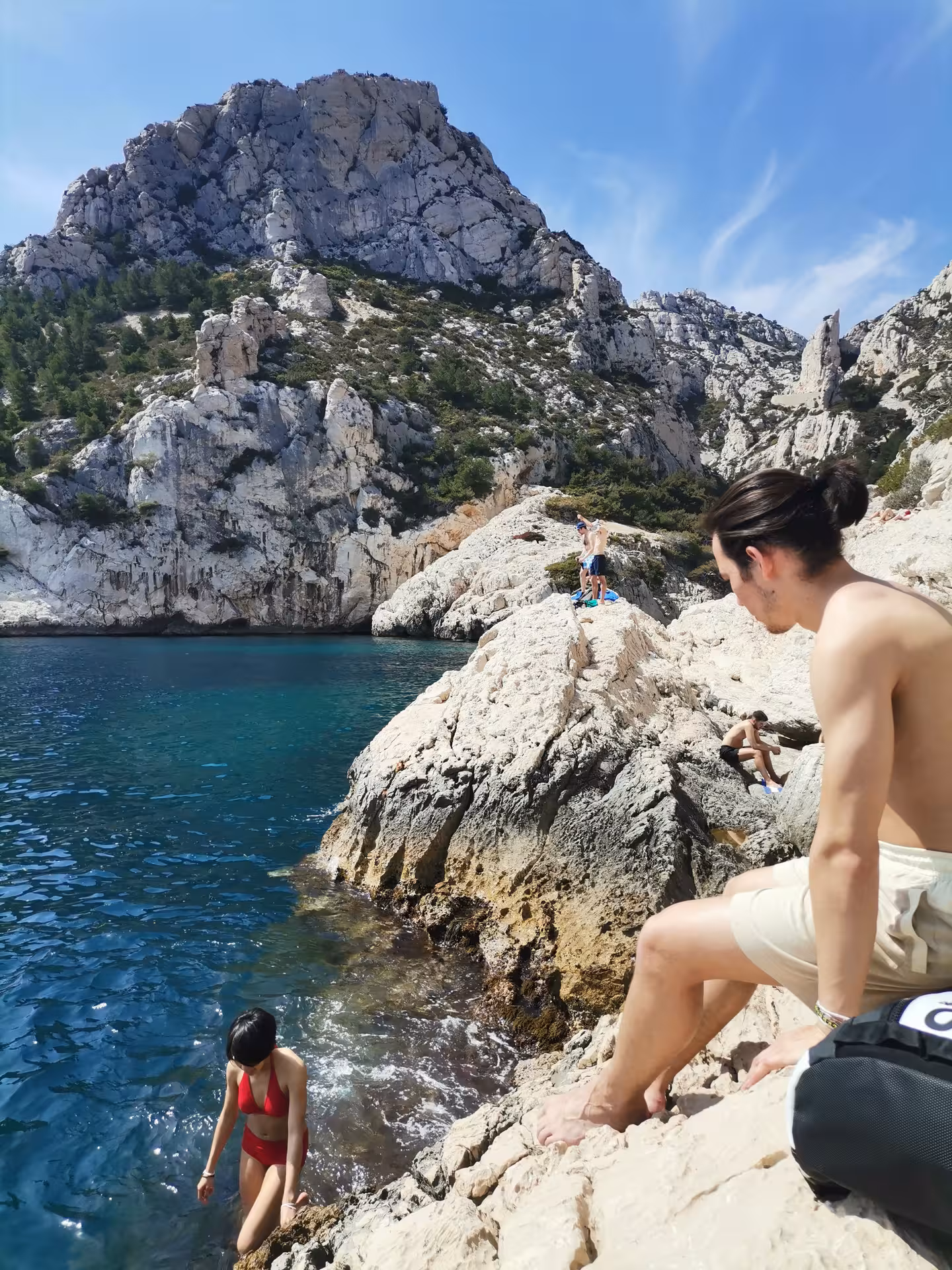 Adventurers on limestone rocks by deep-blue Calanques waters, coastal trekking highlight of the 14-day Provence getaway