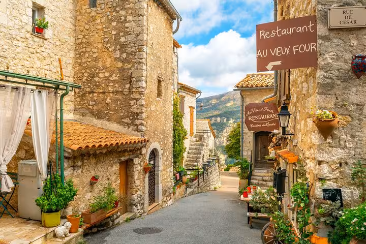 Quaint Provençal street with rustic stone buildings and a cozy restaurant, ideal for exploring countryside charm.