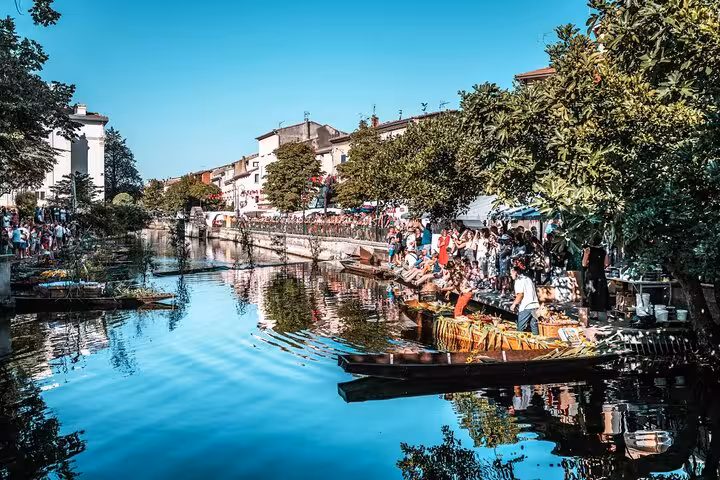 Bustling market along a serene canal in Provence, showcasing local culture and vibrant community life.