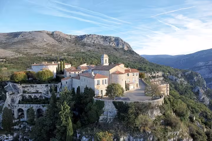 Aerial view of a charming Provence village perched on a hill with stunning mountain backdrop.