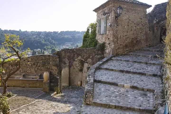 Rustic cobblestone steps winding through a serene Provence village with scenic countryside views.