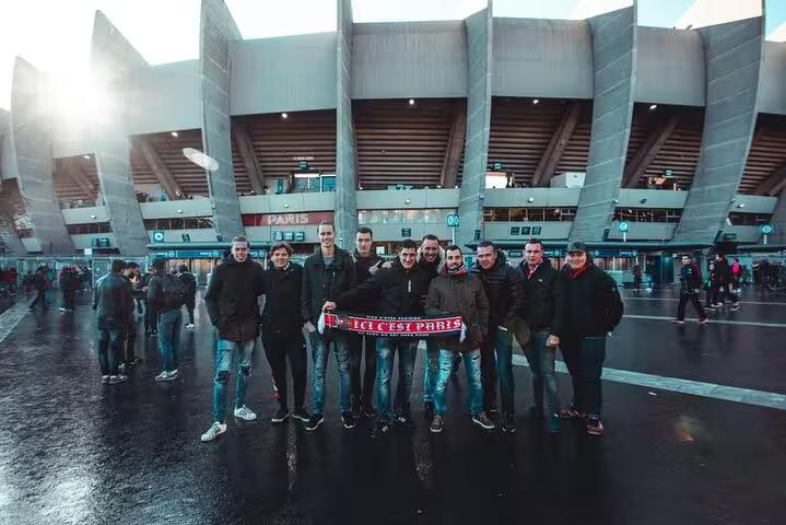 PSG matchday tour group holding a Paris Saint-Germain scarf at Parc des Princes stadium entrance in Paris