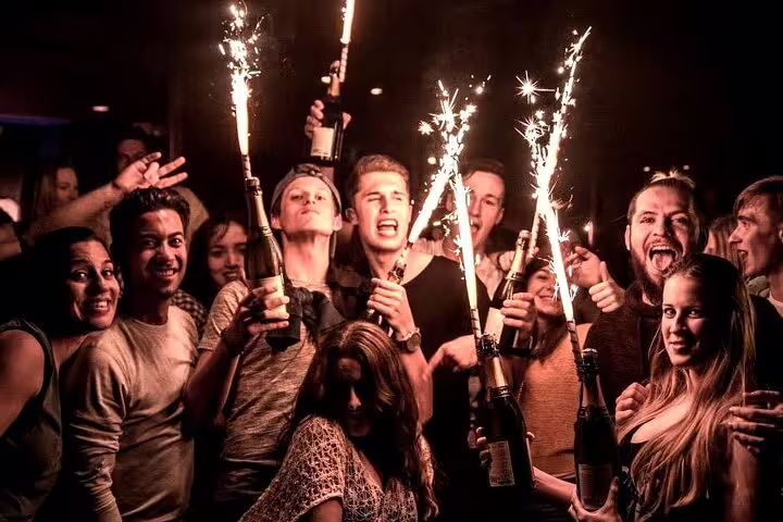 A lively group celebrates during the Pub Crawl Madrid by Mad Party Crew, holding sparklers and bottles in a vibrant nightlife scene.