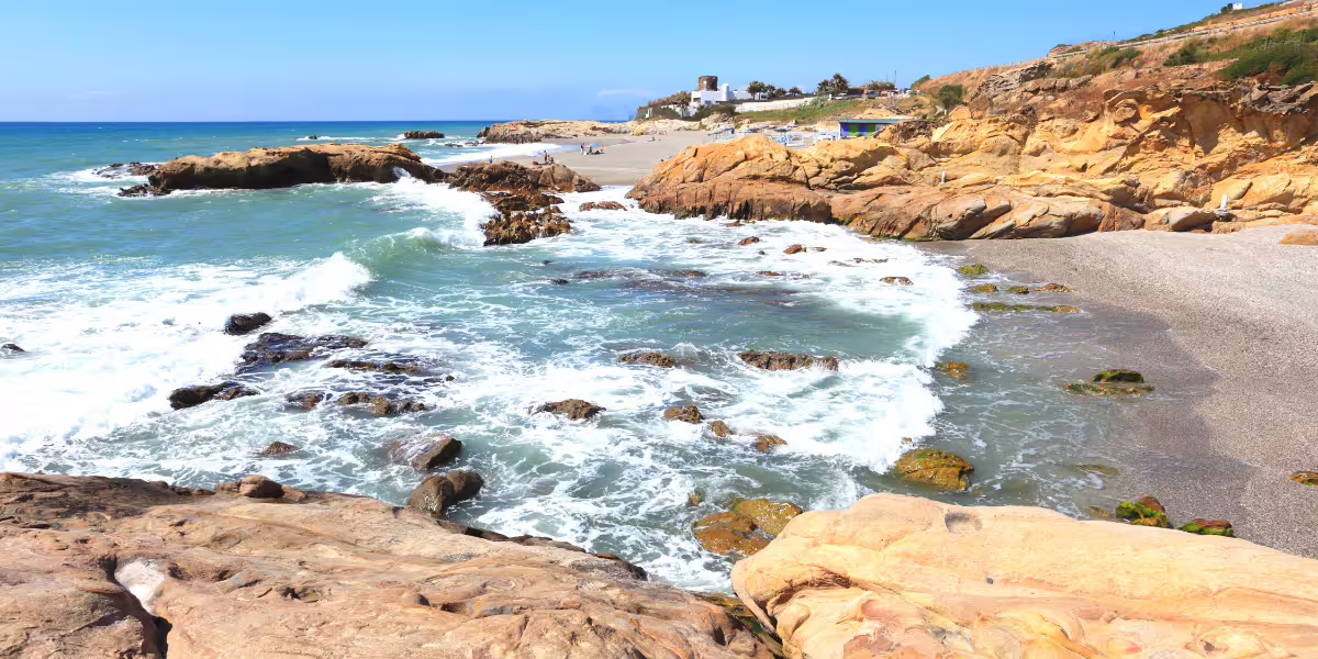 Rocky shoreline and waves crashing on Puerto de la Duquesa beach, perfect for a scenic minicruise experience.
