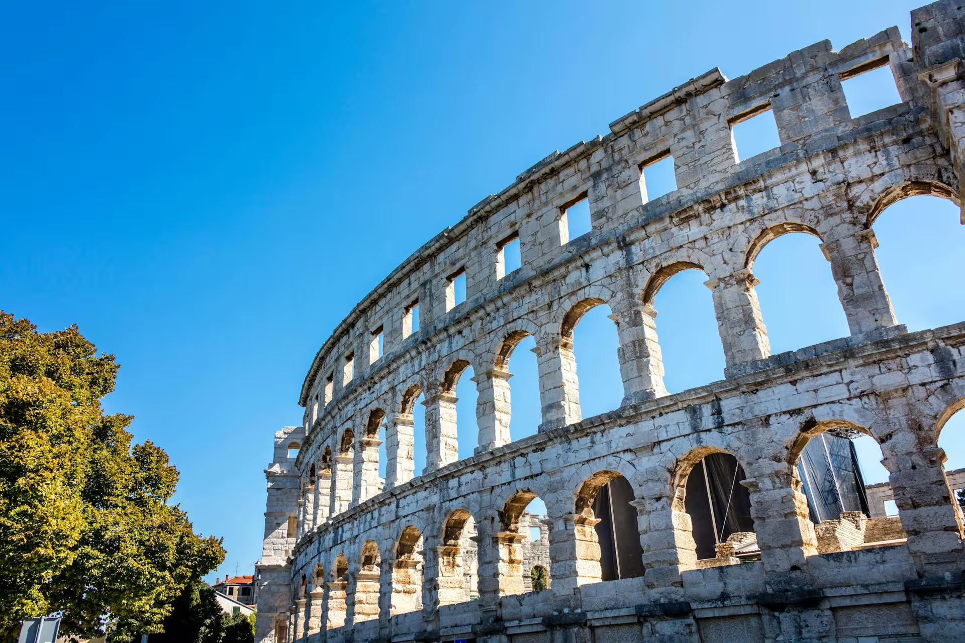 Exterior arches of the Pula Arena amphitheatre under blue sky on the Ancient Istria day trip from Poreč