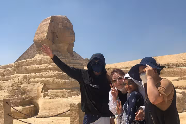 Tourists pose by the Great Sphinx on a private Pyramids of Giza tour with guide, camel ride and lunch