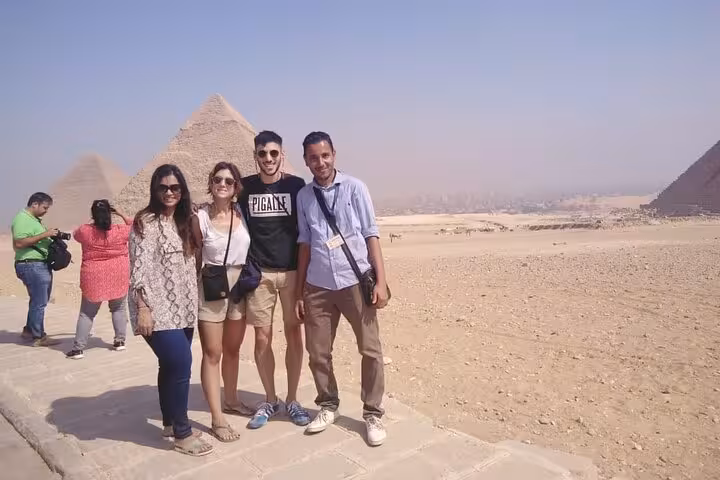 Travelers with guide posing at the Pyramids of Giza on a private tour with camel ride option and lunch