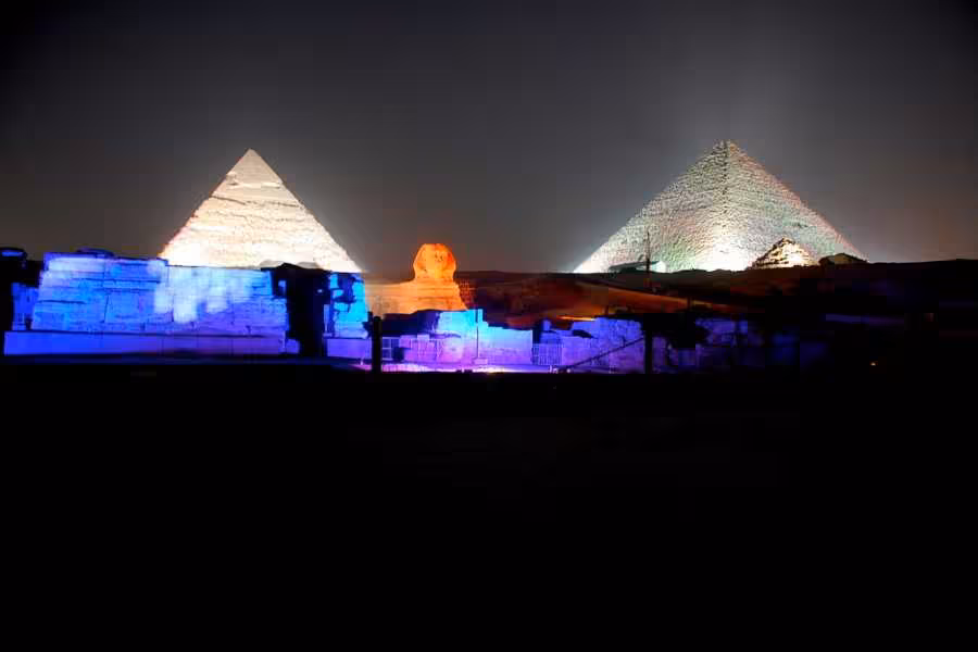 Pyramids of Giza Sound and Light Show with Sphinx glowing and colorful lights on ruins at night, Cairo