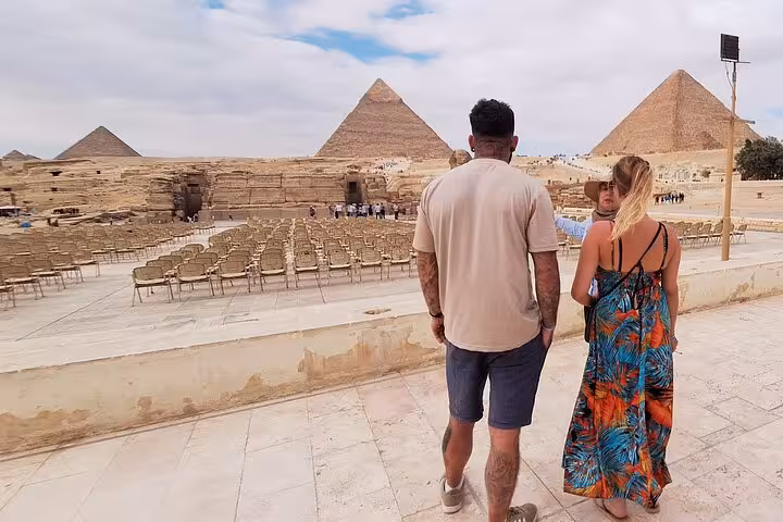 Visitors exploring the historic site of the Pyramids of Giza, showcasing ancient architecture and open seating area.