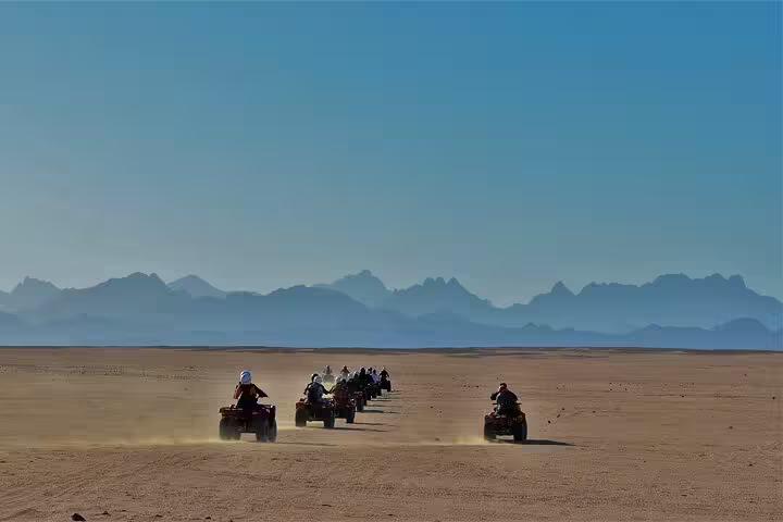 Group of riders on ATVs crossing the Sharm El Sheikh desert at sunrise, quad biking with mountain views