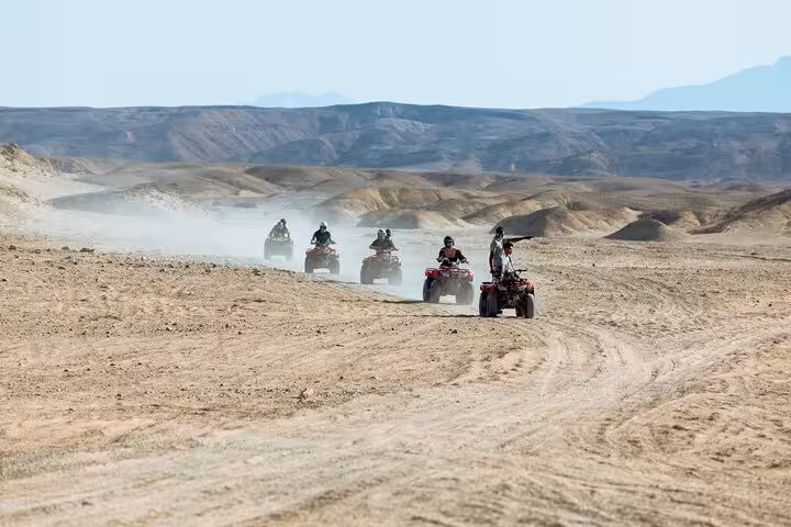 ATV convoy crossing Marsa Alam desert trails, quad safari adventure with camel ride, Bedouin village and dinner