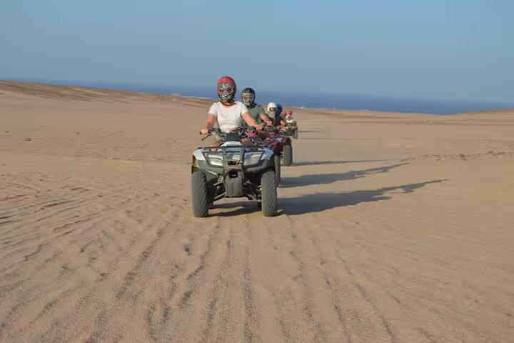 Group ATV quad biking across Sharm El Sheikh sand dunes near the sea, sunrise or sunset desert adventure