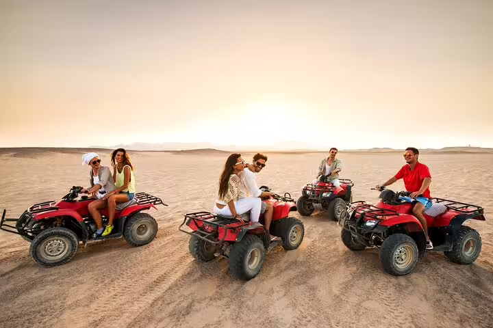 Friends gathered on quad bikes in the desert, enjoying an adventurous ride at sunset with vast open skies.