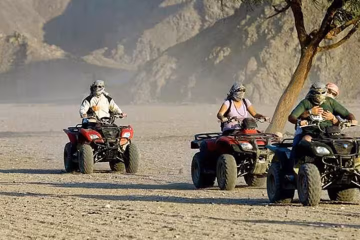 Group riding quad bikes near mountains in Marsa Alam, desert safari with camel ride, Bedouin village and dinner