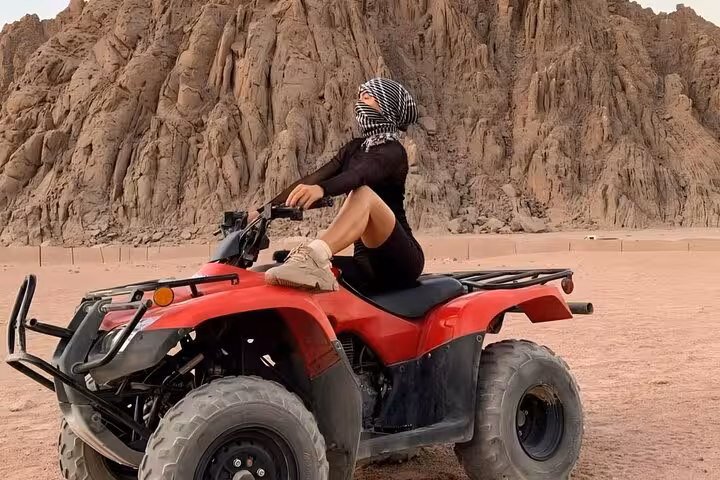 Woman on red quad bike in Marsa Alam desert, part of quad safari with camel ride and Bedouin dinner