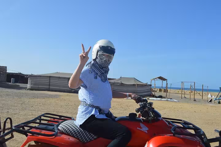 Rider on red quad in Marsa Alam desert camp, part of quad safari with camel ride, Bedouin dinner