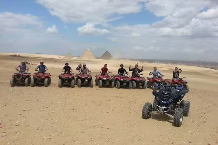 Group quad biking in Giza Desert with Great Pyramids backdrop on guided desert safari tour