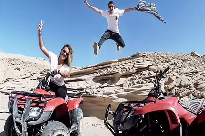 Friends posing with red ATVs on desert rocks near Giza, fun 1-hour quad bike safari at sunrise or sunset
