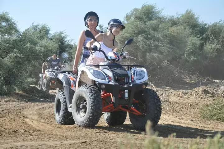 Two women on a quad bike exploring rugged trails surrounded by lush greenery in Kusadasi, Turkey.