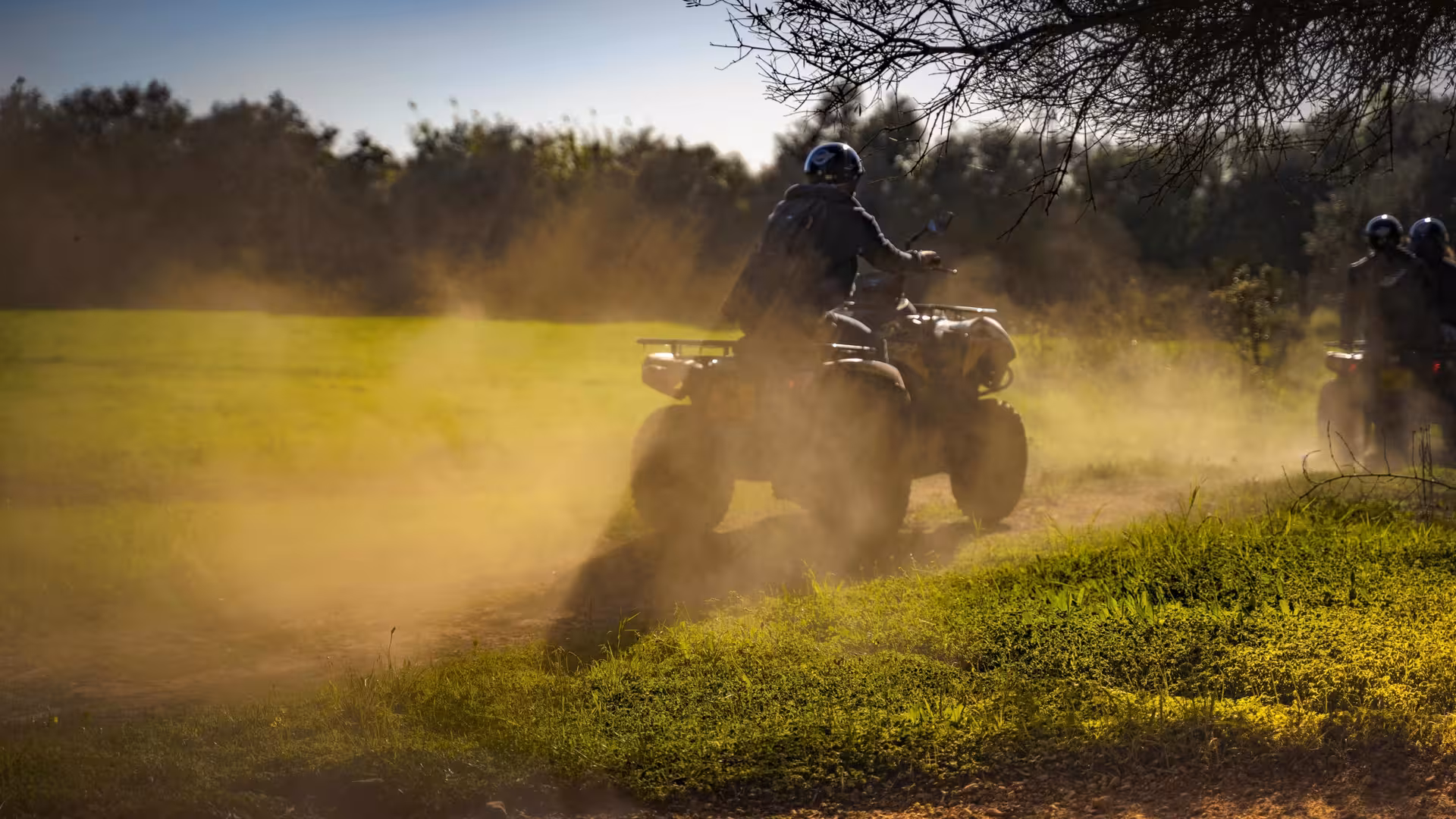 Rider kicks up dust on a powerful quad bike during a half-day off-road ATV tour through sunny countryside trails.