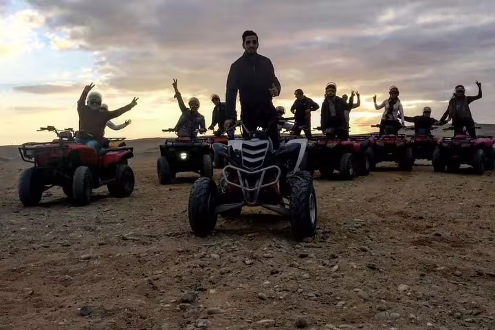 Riders posing on quad bikes at sunset in Giza Desert, Egypt, on pyramids ATV safari excursion