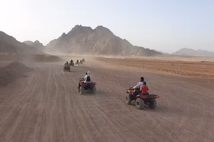 Quad biking in Sinai Desert from Sharm El Sheikh, riders speeding past mountains on Super Safari tour