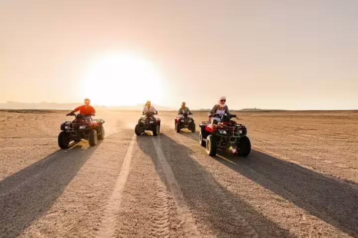 Group of riders on quad bikes crossing the Sinai desert at sunset on a private ATV tour from Sharm El Sheikh