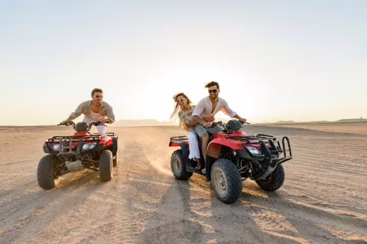 Friends riding quad bikes across Sinai desert at sunset on a private ATV safari tour from Sharm El Sheikh