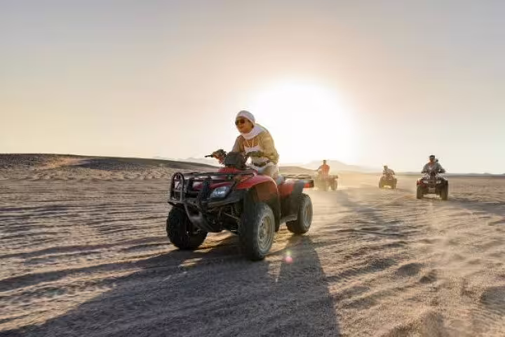 Rider on quad bike with convoy at sunset in Sinai Desert, private ATV safari adventure from Sharm El Sheikh