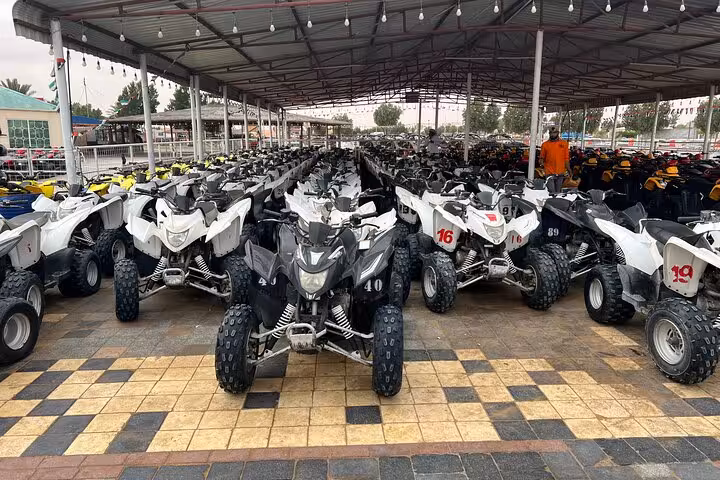 Fleet of quad bikes lined up for desert ATV tour, ready for dune riding, safety briefing and rental check-in