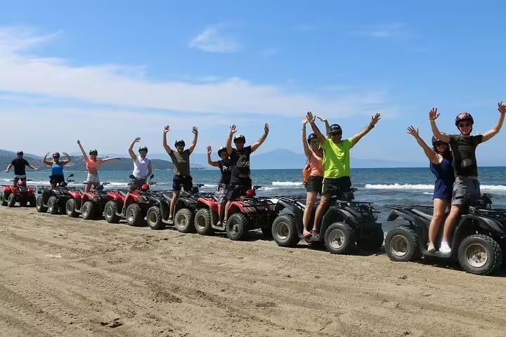 Group of happy tourists on quad bikes along a scenic beach, part of the Kusadasi Port cruise excursion adventure.
