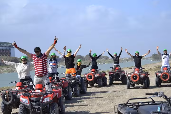 Group on ATVs with helmets celebrating by the river on Antalya quad safari tour with scenic views
