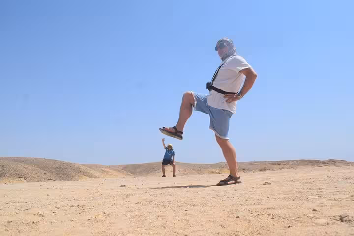 Fun desert photo stop during Marsa Alam quad safari to Bedouin village and camel ride, wide sandy landscape
