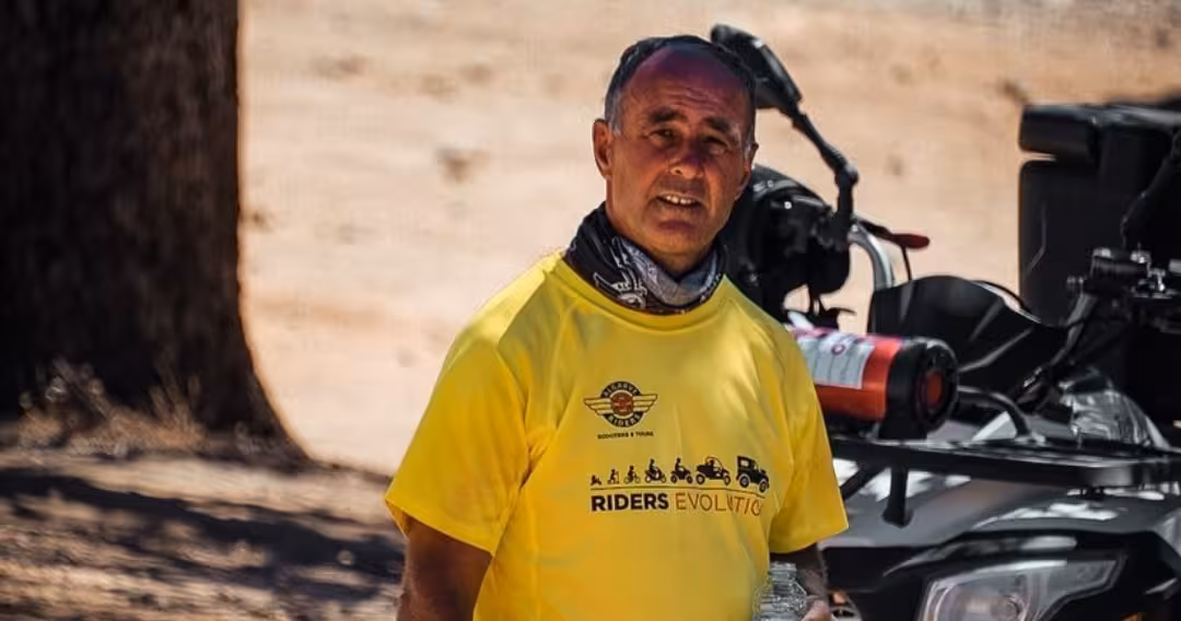 Friendly quad tour guide in yellow Riders Evolution shirt standing beside an ATV during a full day off-road excursion