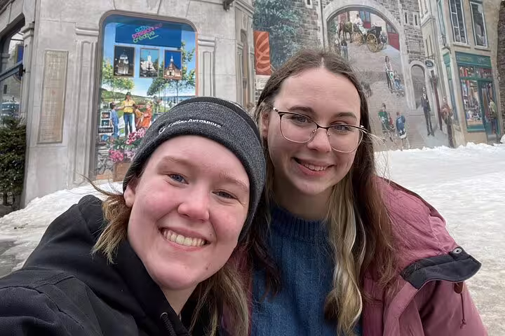 Smiling travelers in snowy Old Quebec during a Quebec City scavenger hunt walking tour near murals