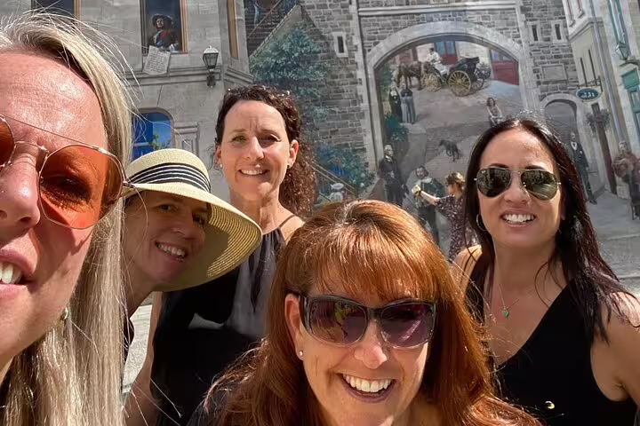 Friends taking a selfie by Old Quebec City mural, enjoying a Quebec City scavenger hunt and highlights walk