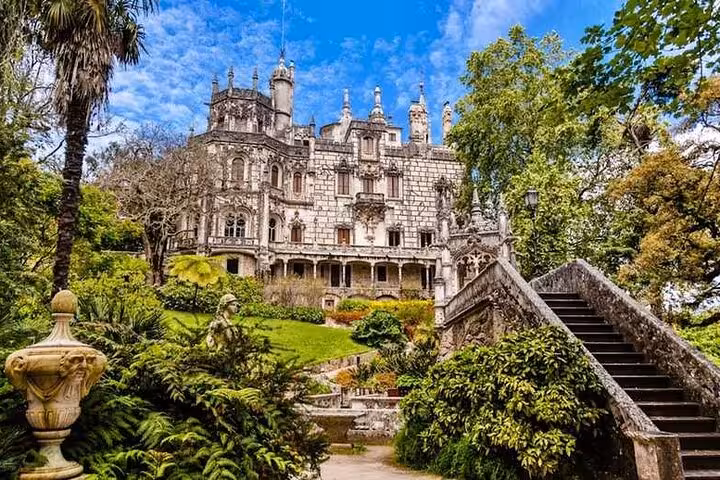 Enchanting Quinta da Regaleira estate surrounded by lush greenery in Sintra, featuring Gothic-style architecture and gardens.